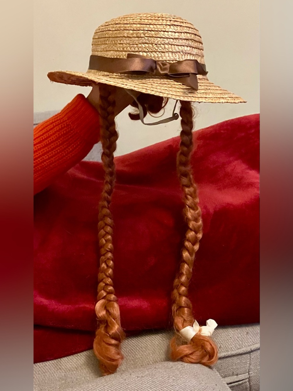 Straw hat with orange hair that is braided